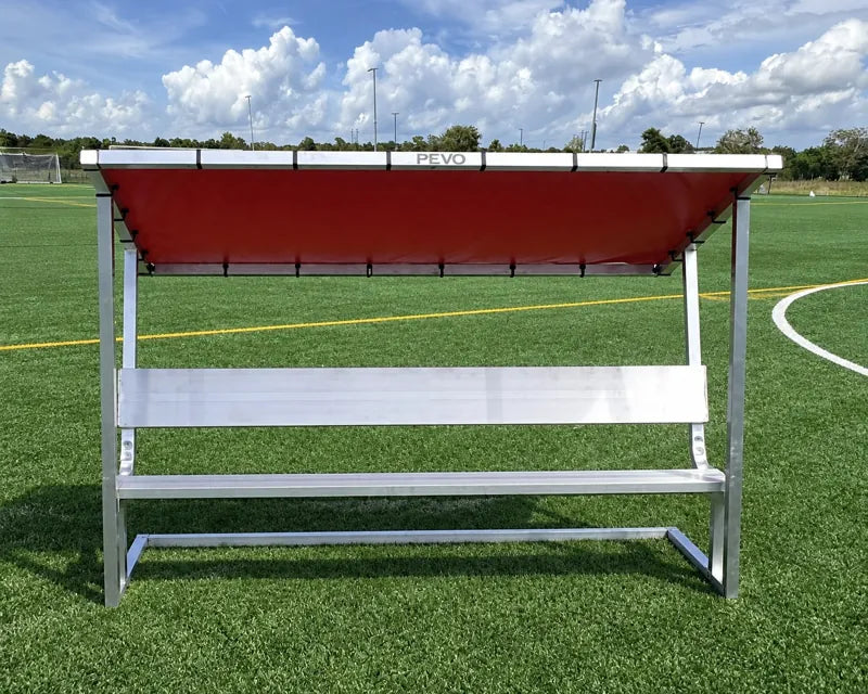 Front view of a 7.5ft aluminum covered bench with a plain red tarp on a turf soccer field.