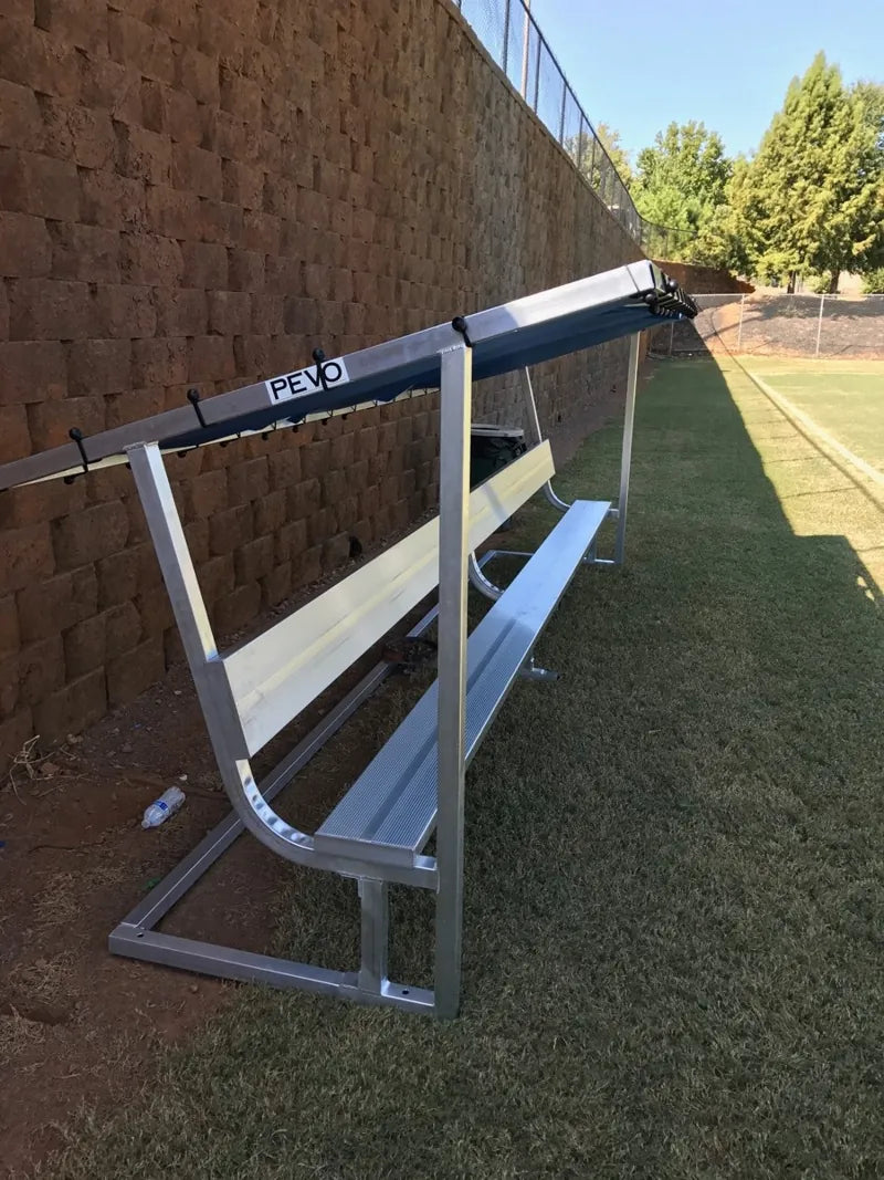 Side view of a Roswell aluminum covered bench with a blue tarp beside a stone retaining wall.