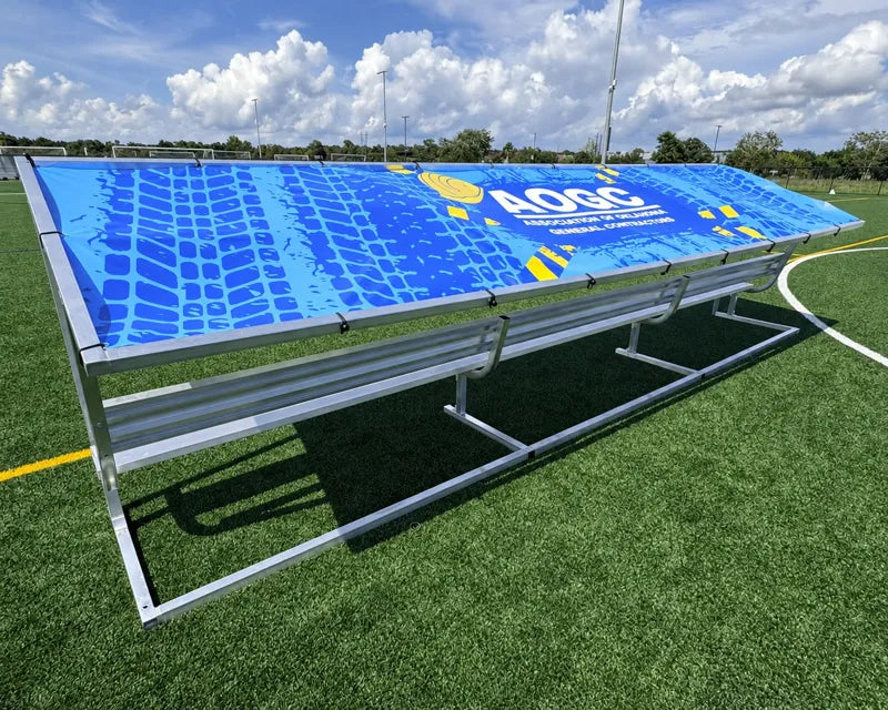 Rear angled view of a 21ft aluminum covered bench with a blue patterned tarp and white AOGC logo.