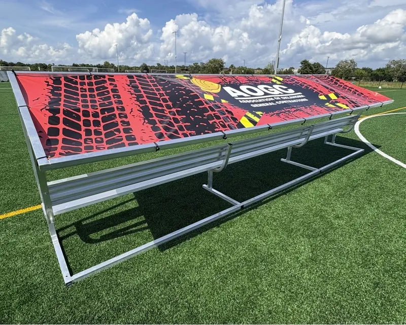 Rear angled view of a 21ft aluminum covered bench with a red and black patterned tarp and white AOGC logo.