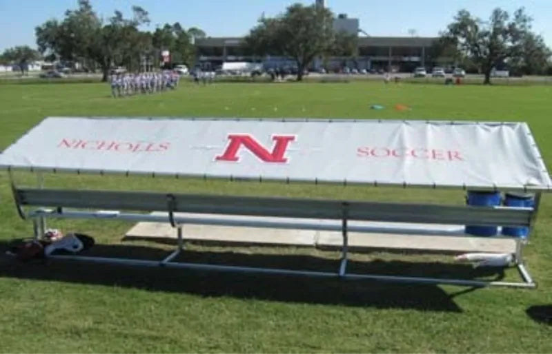 Rear view of a Nicholls College covered bench with a white tarp, red N logo, and red lettering.