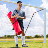 Athlete carrying agility pole set bag on a soccer field in front of a goal