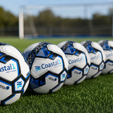 Line of Coastal1 Credit Union custom soccer balls on a turf field with a soccer goal in the background.