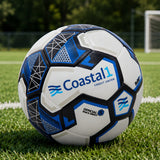 Customized Coastal1 Credit Union soccer ball displayed on a grass field with a soccer goal in the background.