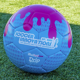 Close-up of the blue and pink Drip Soccer Ball showing textured surface and bold drip design on artificial turf