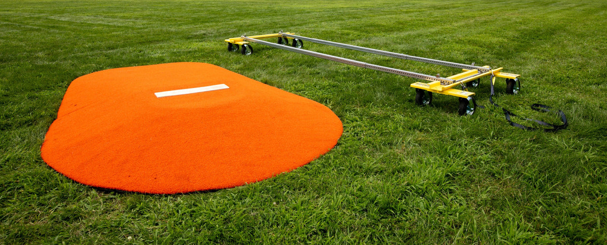Portable pitching mound next to assembled Mound Taxi system on grass field