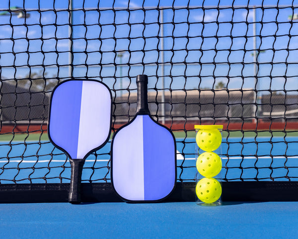 Pickleball paddles and balls displayed on a pickleball court with net