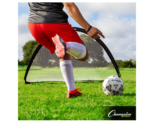 Youth soccer player in red shorts practicing with portable half-moon pop-up soccer goal on grass field, Champion Sports Elite 5 ball positioned for backyard training session