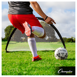 Youth soccer player in red shorts practicing with portable half-moon pop-up soccer goal on grass field, Champion Sports Elite 5 ball positioned for backyard training session
