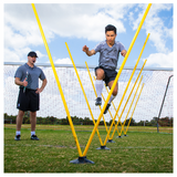 Athlete performing agility ladder style drill through Pro Agility Pole Set with coach supervising on soccer field