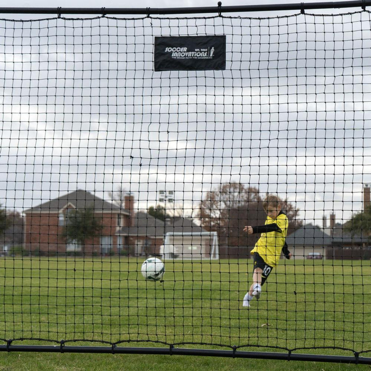 Person playing soccer on a field with a goal net in the foreground