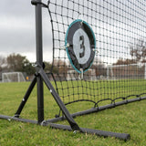 Goalie training device with a brand logo attached to a soccer net on a grass field.