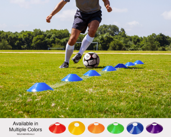 Soccer player dribbling ball through blue disc cones during agility training on grass field