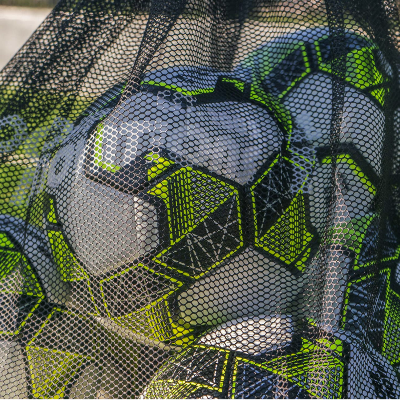 Detailed close-up of white and neon yellow soccer balls stored inside a black mesh soccer ball bag