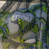 Detailed close-up of white and neon yellow soccer balls stored inside a black mesh soccer ball bag